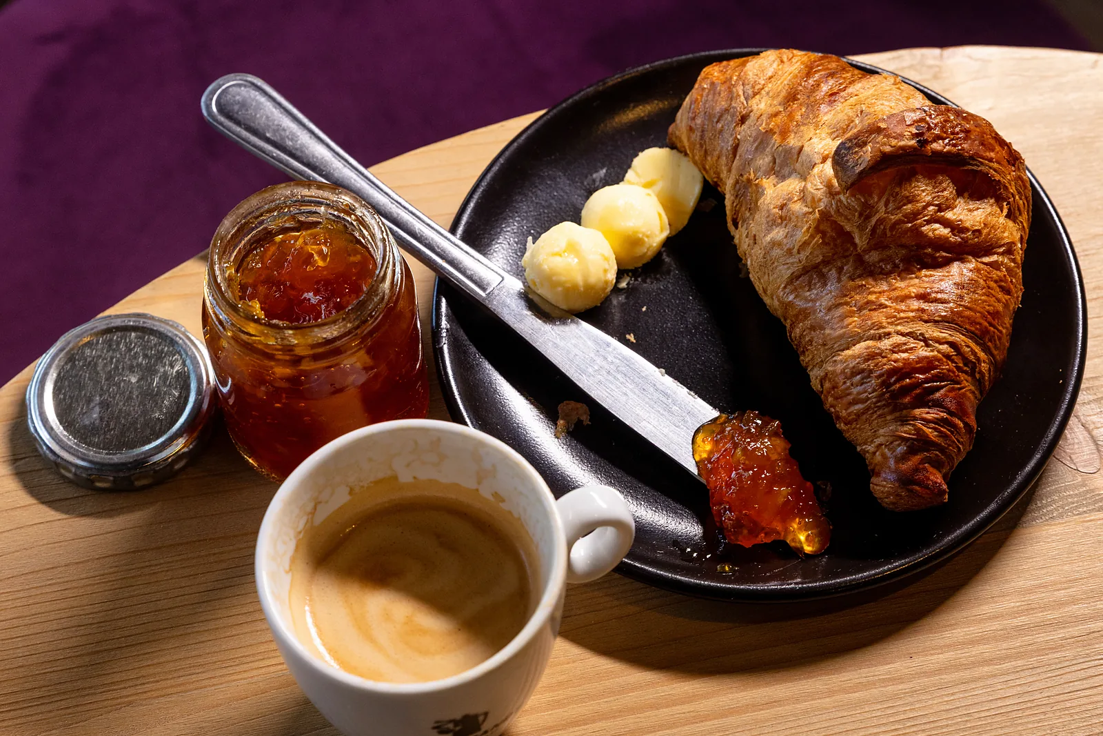 Croissant with butter, jam and coffee on a breakfast table at Plumwood Boutique Hotel