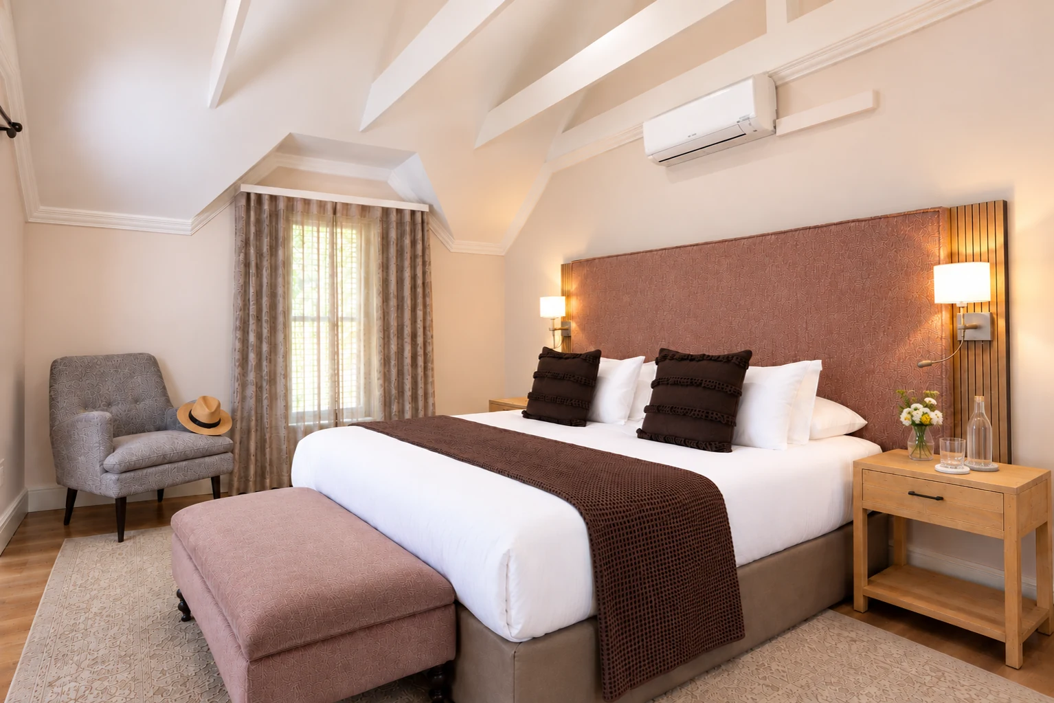 Deluxe Room with a king bed, rose headboard and sloped beamed ceiling at Plumwood Boutique Hotel