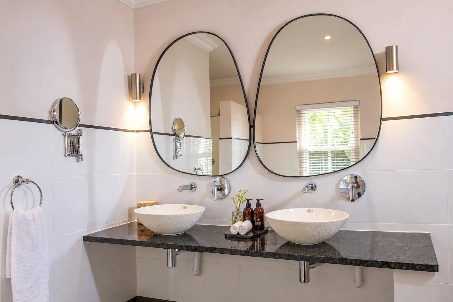 Twin basins under two pebble-shaped mirrors in a Plumwood Boutique Hotel bathroom