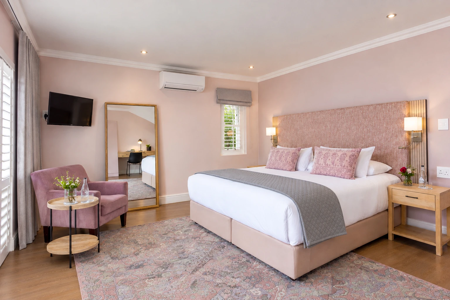 Bedroom with a king bed, pink upholstered headboard and armchair at Plumwood Boutique Hotel
