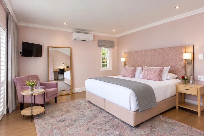 Superior Deluxe Room with a king bed, pink headboard and armchair at Plumwood Boutique Hotel