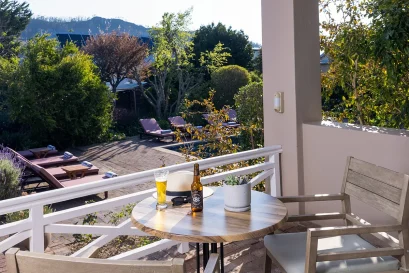 Private balcony with a table and two chairs overlooking the pool and garden at Plumwood Boutique Hotel